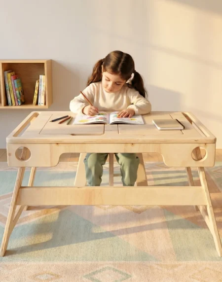 Kız çocuğu ahşap aktivite masasında resim ve çizim yapıyor kitaplıklı oda